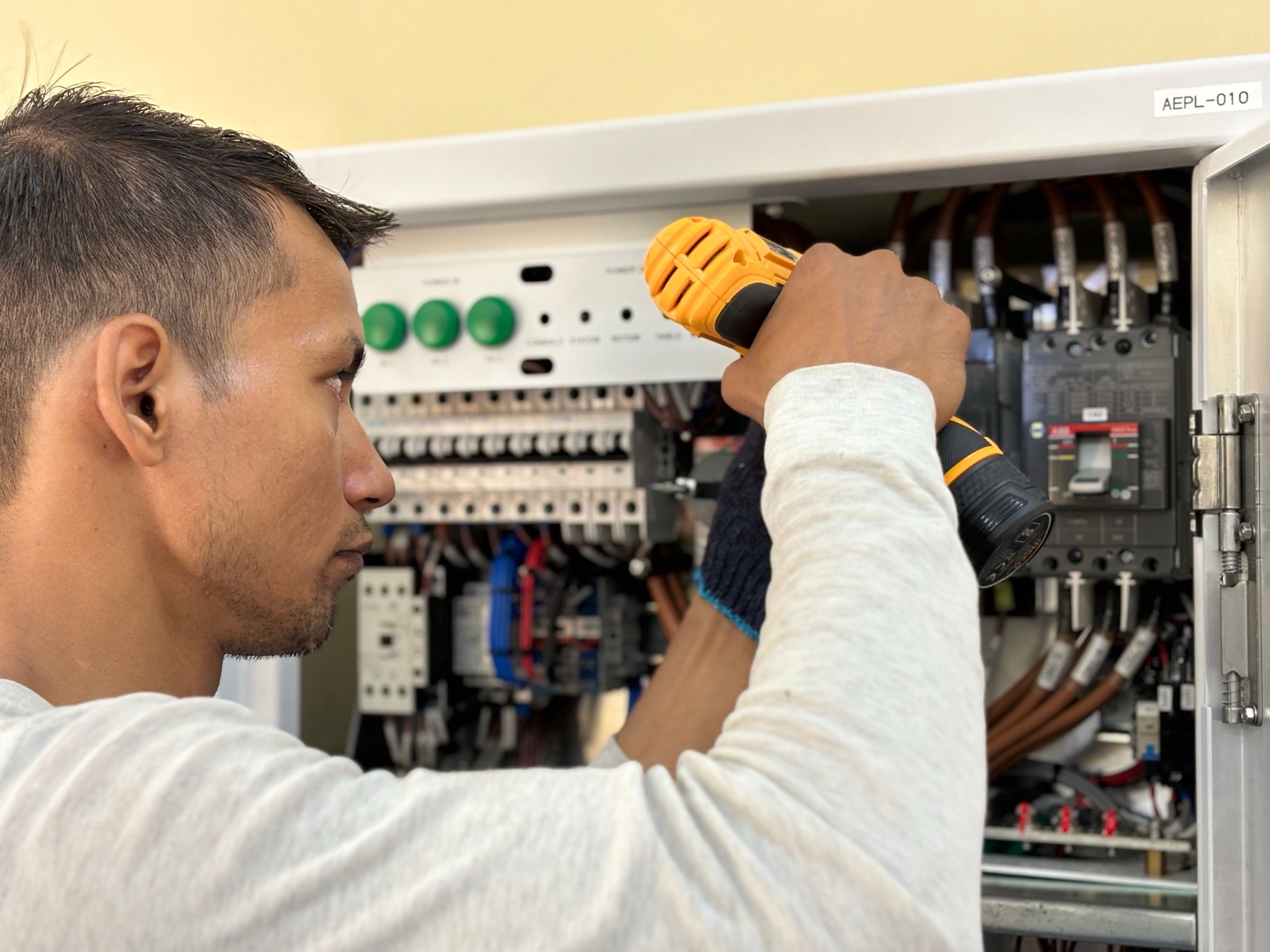 An electrician driving fasteners into a control panel