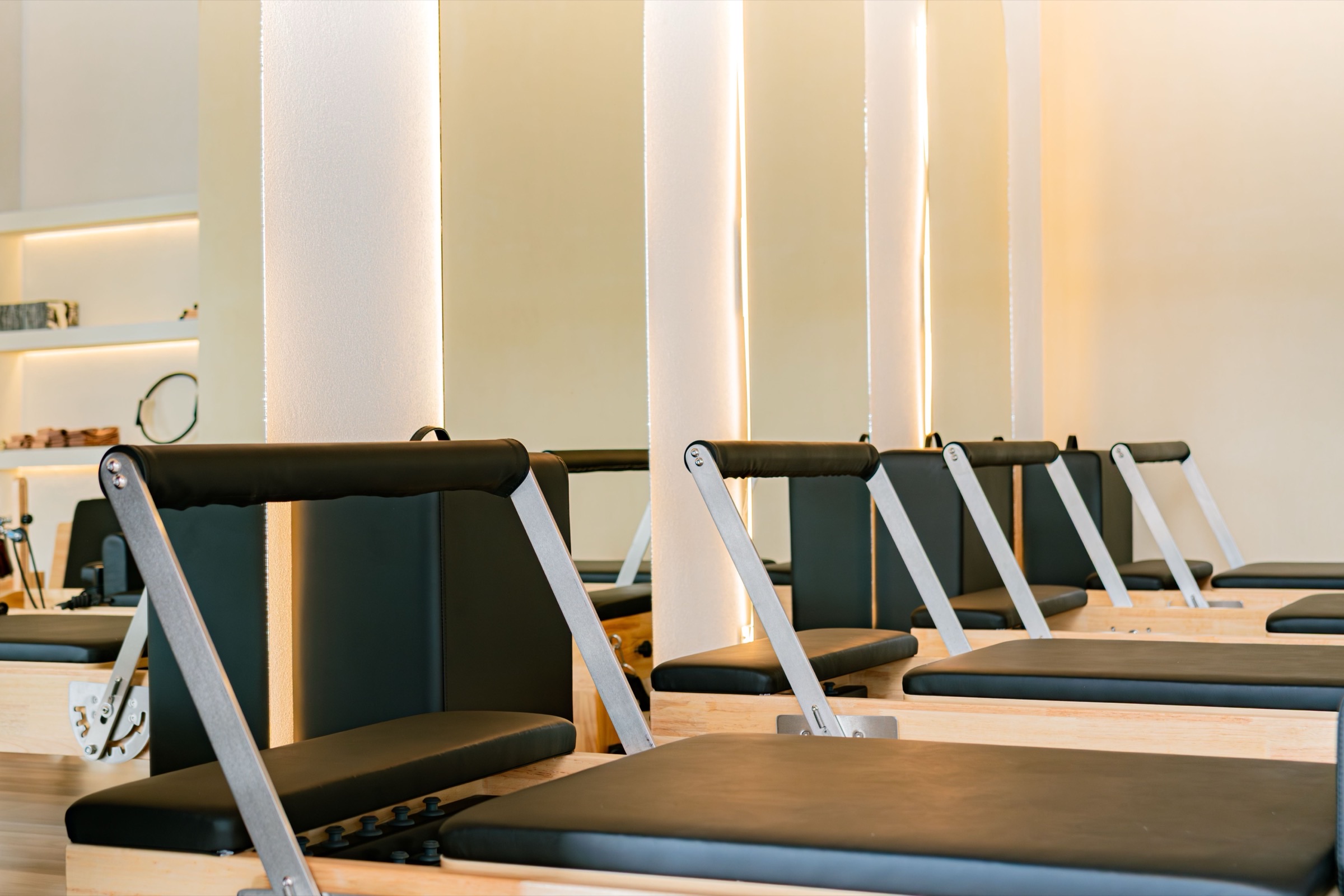 A row of Pilates reformers in a warm boutique studio