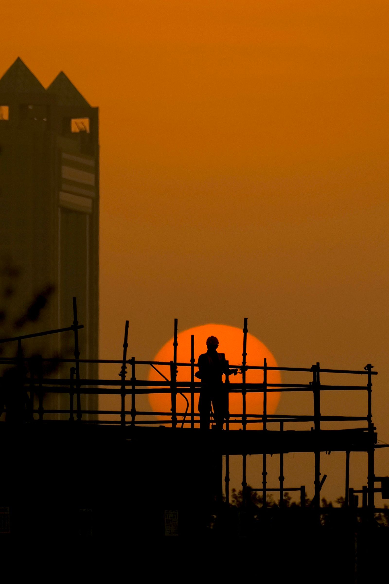 A worker silhouetted against a low sun on a job site