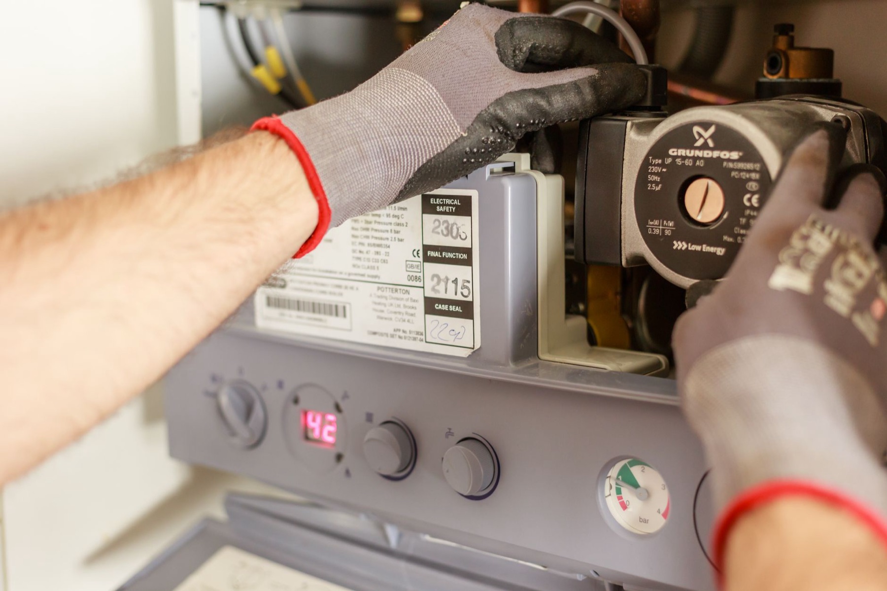 Hands adjusting a boiler system with tools