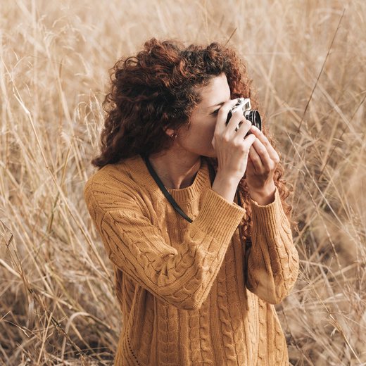 A woman taking a photograph in a wheat field
