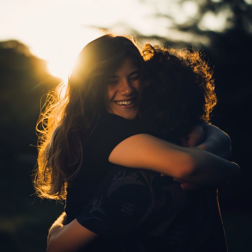Two friends embracing in warm evening light